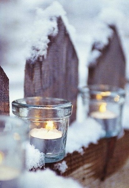 Праздничные свечки в стеклянных стаканах на снегу